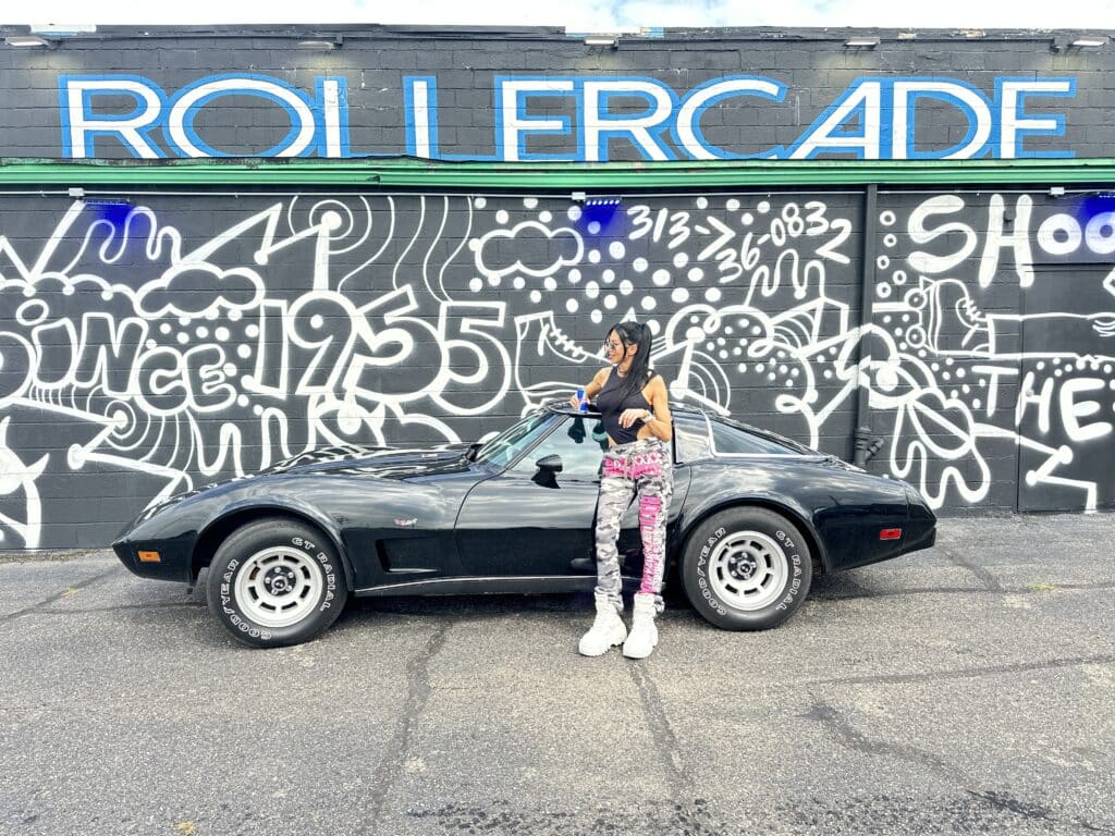 An attendee poses with a classic Corvette outside of the Rollercade in Detroit